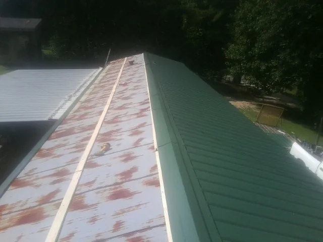 Old rusted panels beside newly installed green metal roofing — Wind Damage Roof Repair by Roofing Brothers in Hephzibah