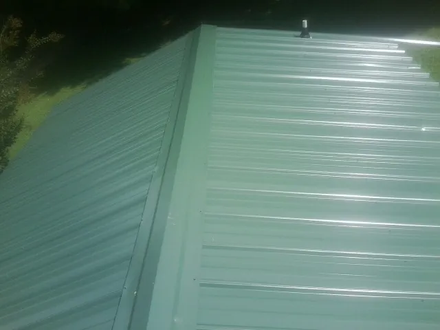 New green metal panels meeting at the ridge of a roof — Flat Roof Repair work by our crew in Hephzibah