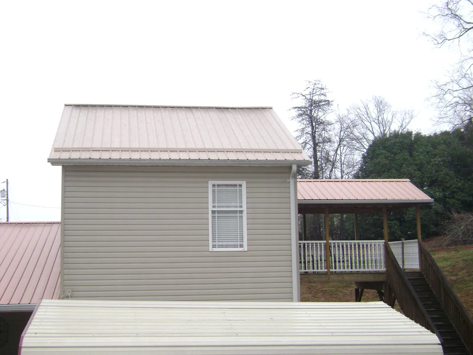 Tan metal roofs on a two story addition and attached porch, from a Roof Replacement job in Hephzibah